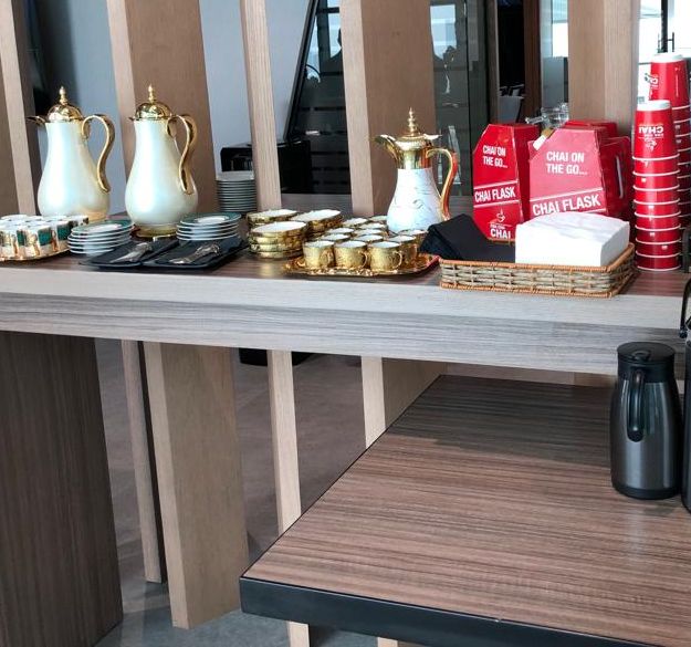 Event table with gold gahwa dallahs, small cups, red Chai Flask boxes and red cups